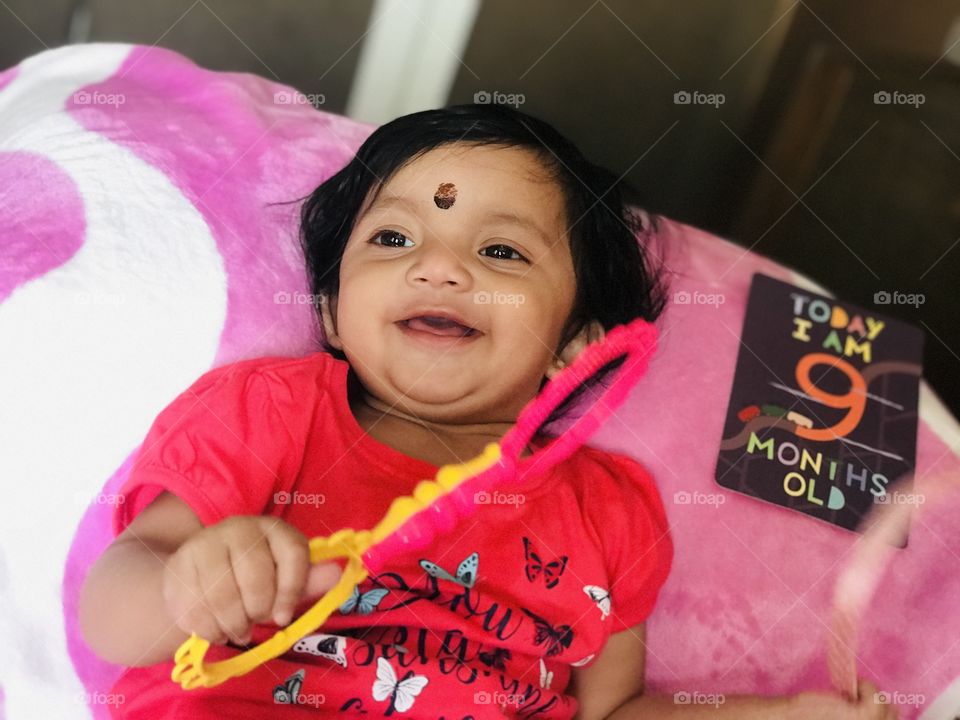 Indian baby with pink dress playing with toy