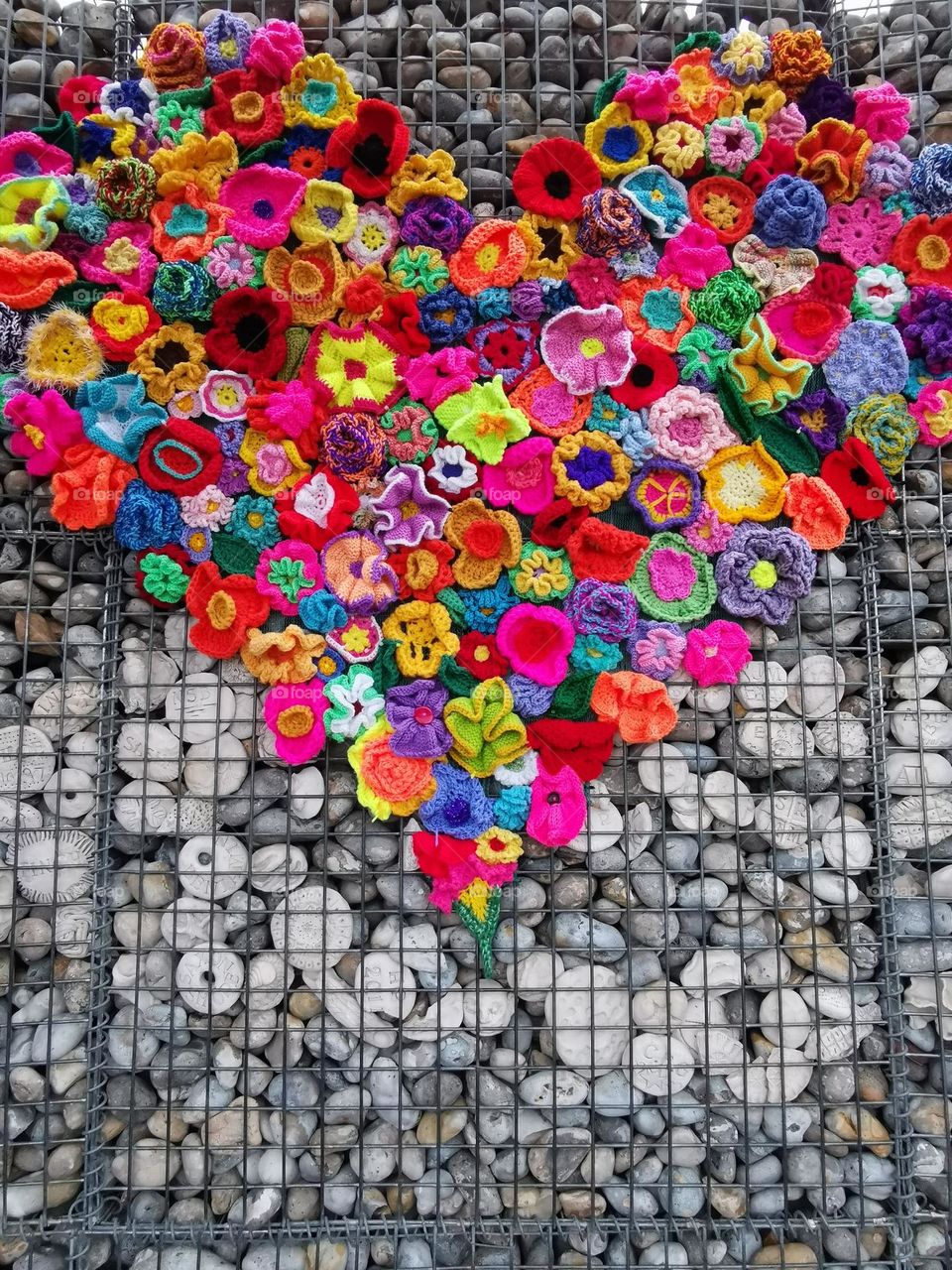 Art object. Knitted flowers and heart. Lots of stones.