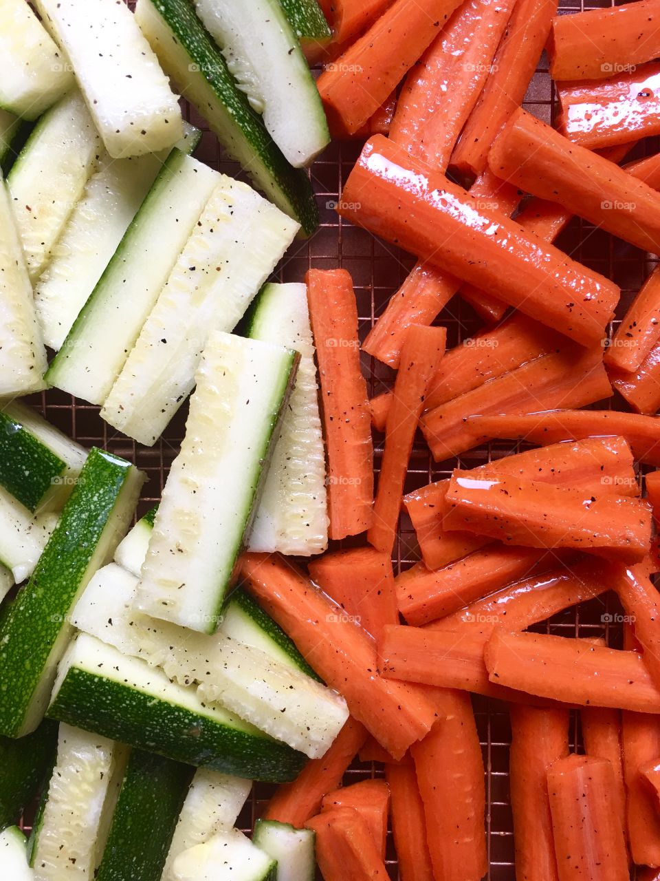 Seasoned zucchini and carrots on a baking pan