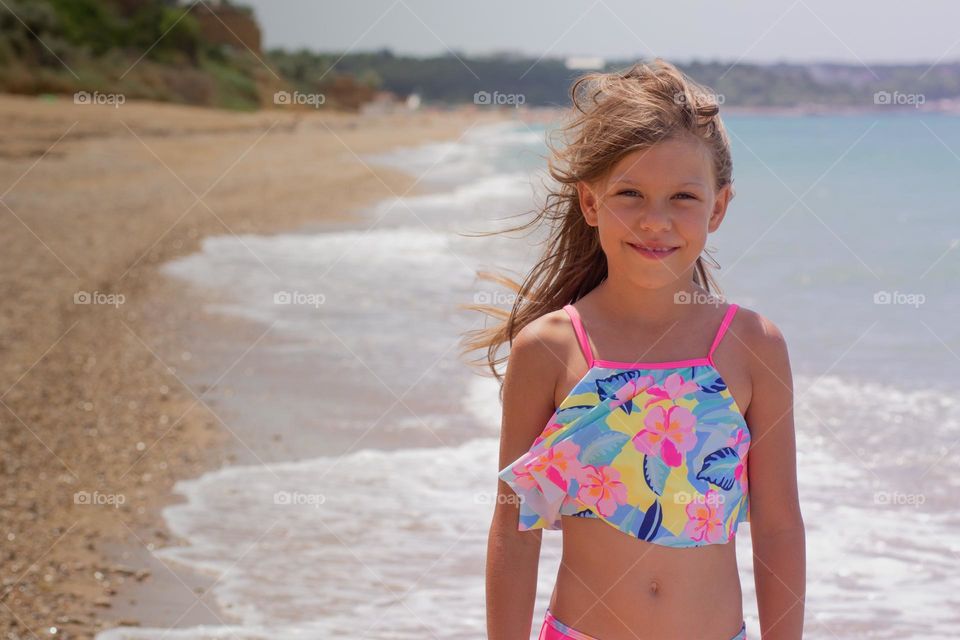 Portrait of beautiful girl of 7-8 years looking at camera on sea background