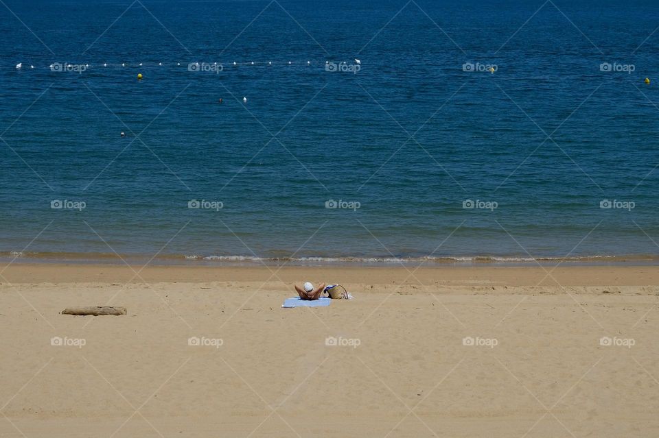 Unrecognizable person laying in the sun by the sea.