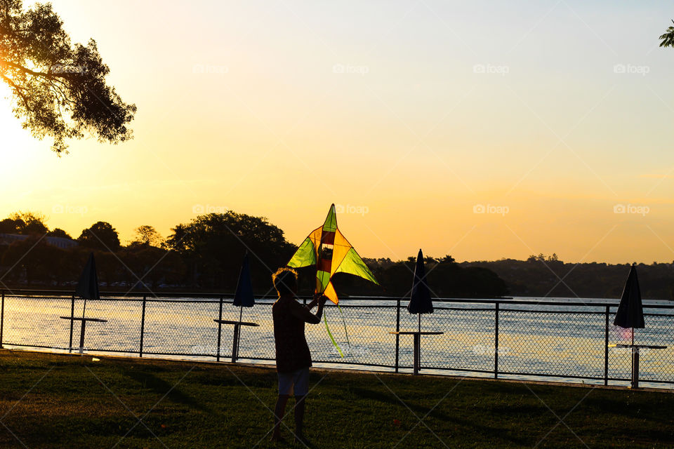 Grandma flying a kite in the park at sunset