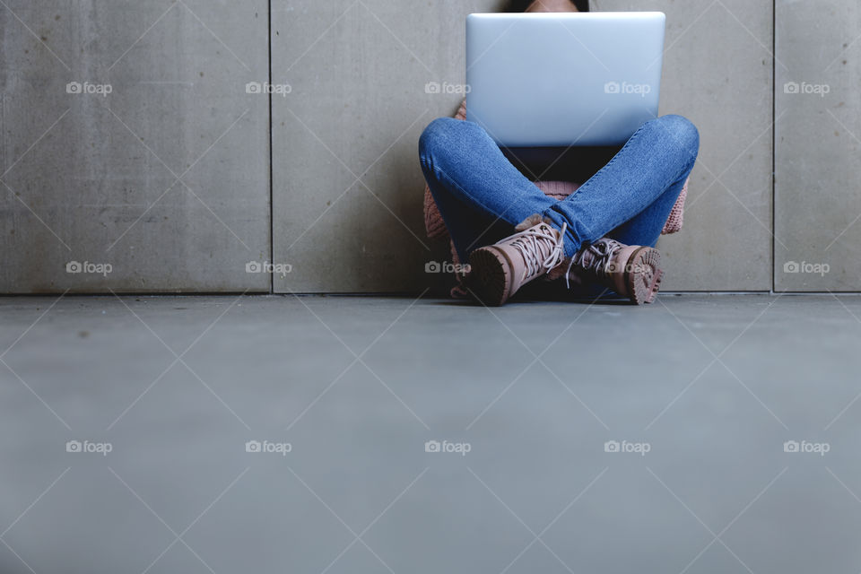 A student sitting on floor and using laptop 