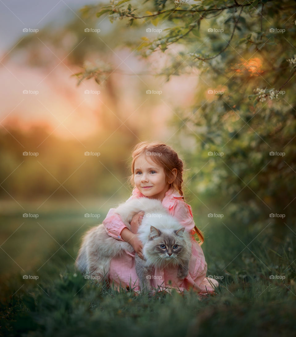 Portrait of a little girl with Neva masquerade cat at sunny evening 