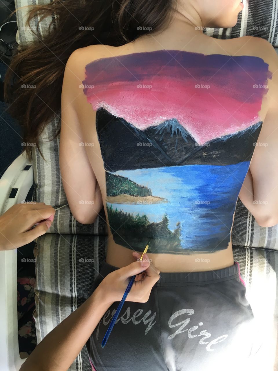 Girls painting on each other's back's, beautiful mountain scenic landscape