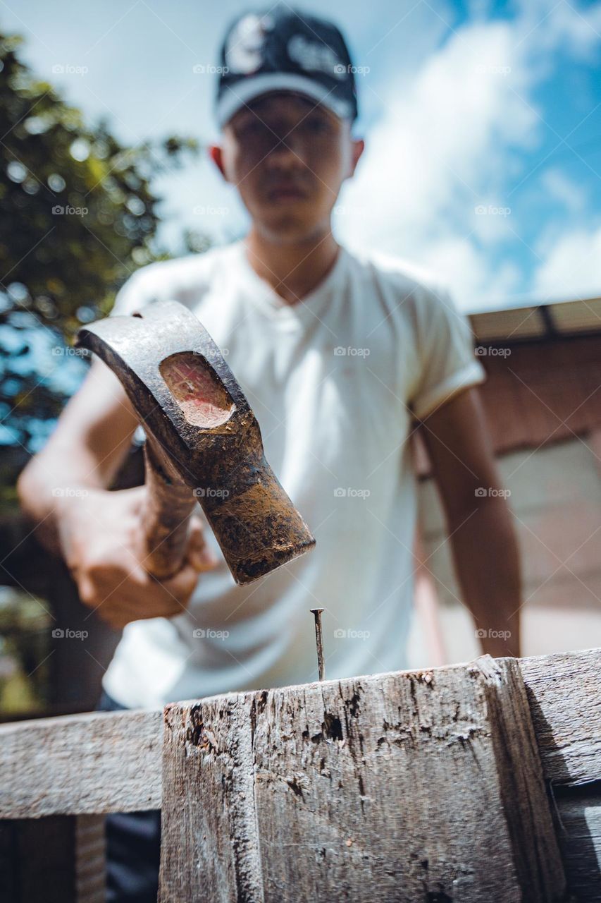 Person hammering a metal nail into wood