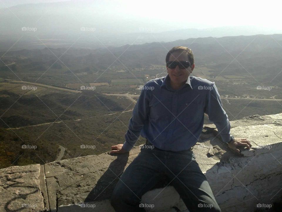 sitting in the edge. sitting on rock fence at top mountain in córdoba,  argentina