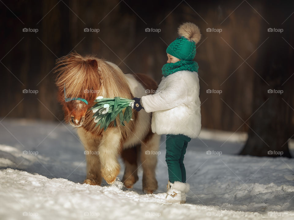 Little girl with pony at early spring day