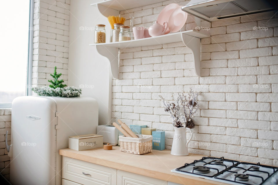 Festive winter cozy kitchen interior with garlands, decorations and gifts.  Christmas dinner at the decorated table.