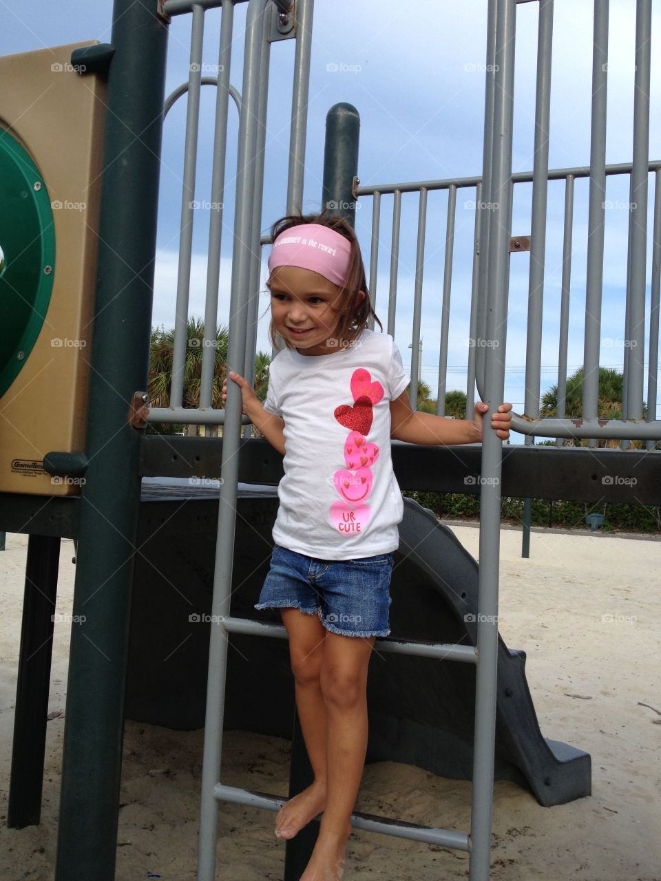 Jungle gym fun . Little girl standing on metal bars of a jungle gym