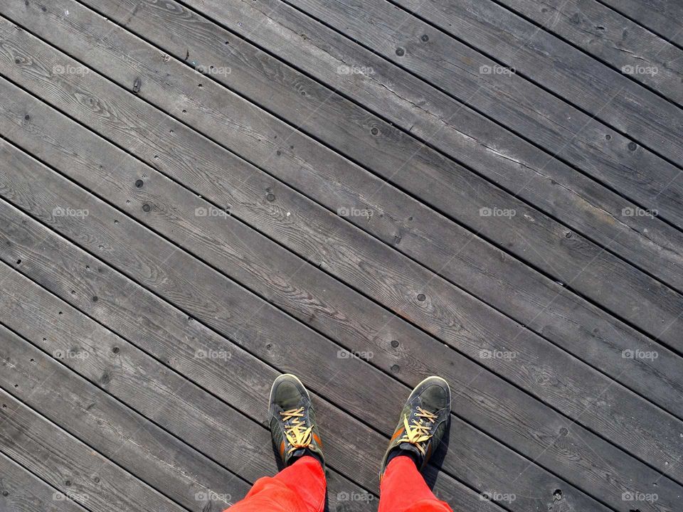 a man in red jeans stands on a wooden floor