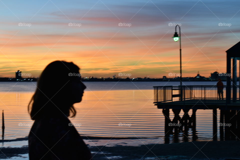 Woman’s silhouette against the colorful sunset in the sky with a lake backdrop