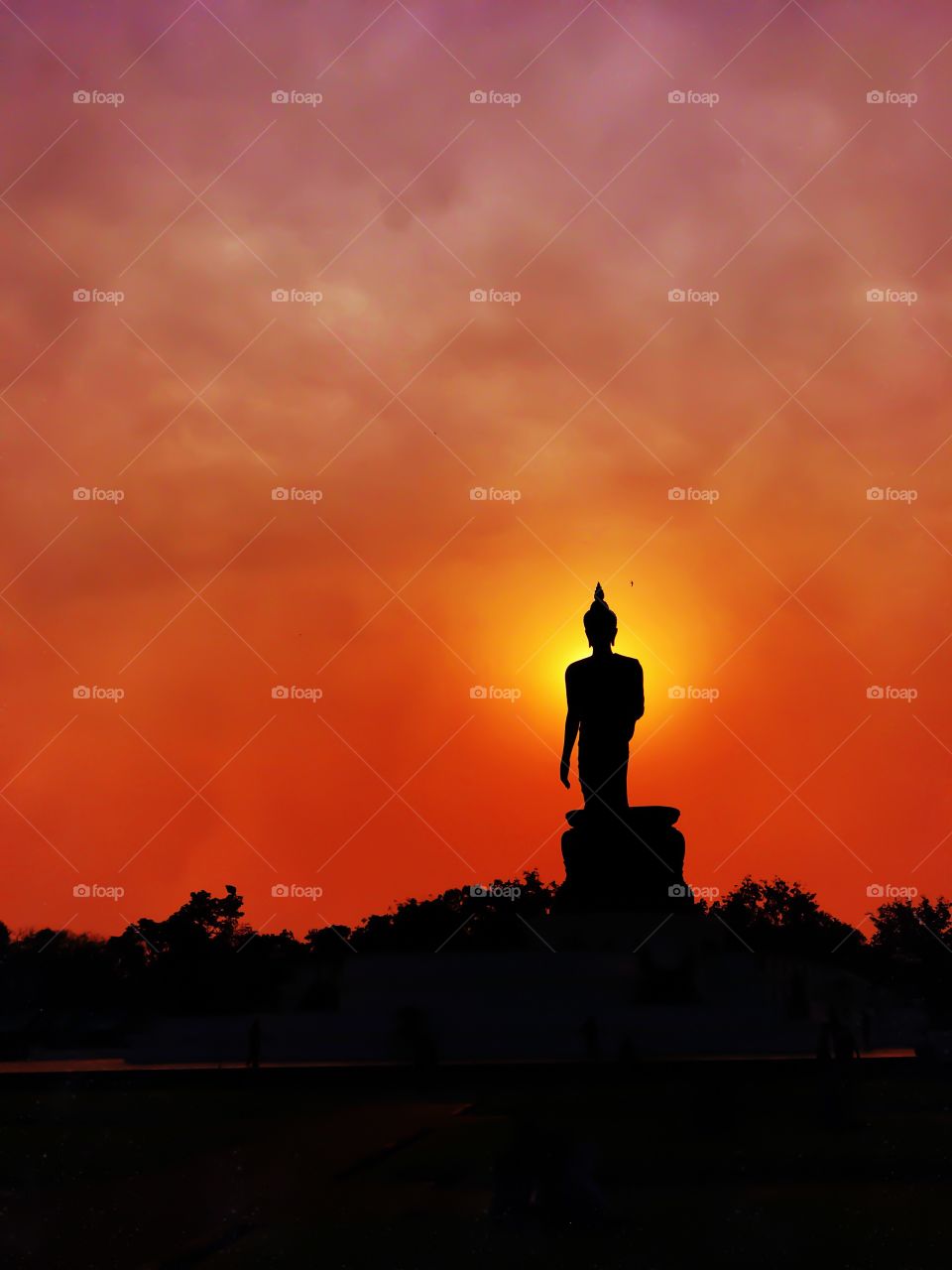Buddha image in walking posture during sunset at Buddhamonthon, Nakhon Pathom, Thailand.