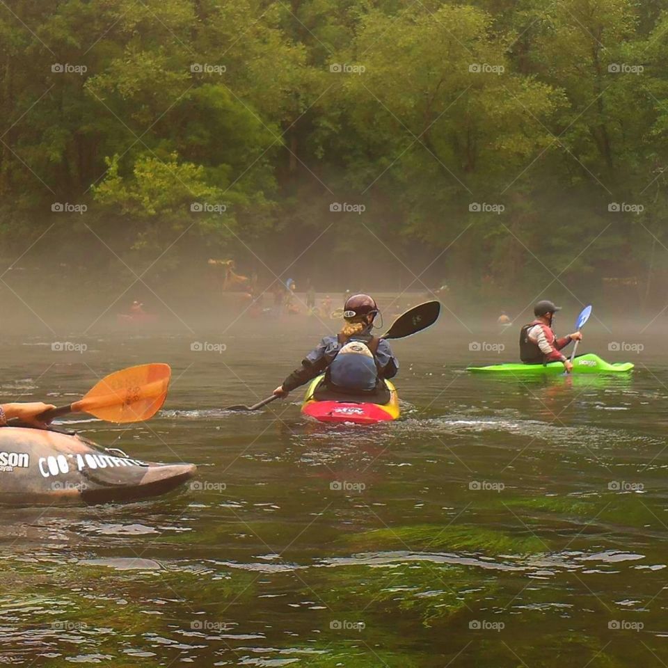 kayakers paddling through fog on the river