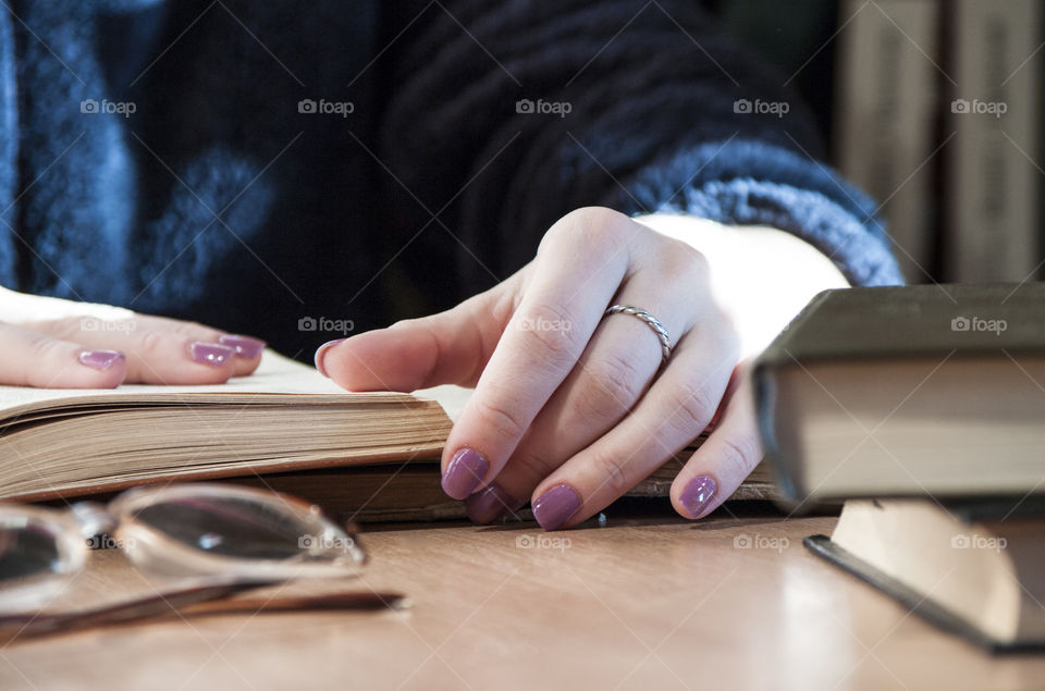 Close-up of woman reading book on desk