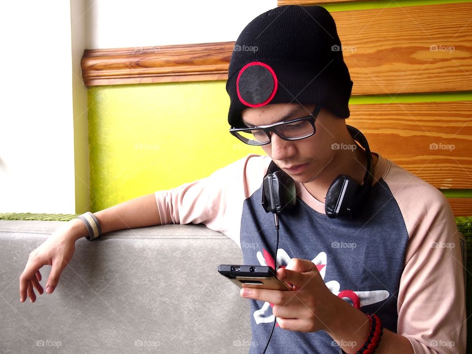 teenage boy wearing bonnet using a smartphone