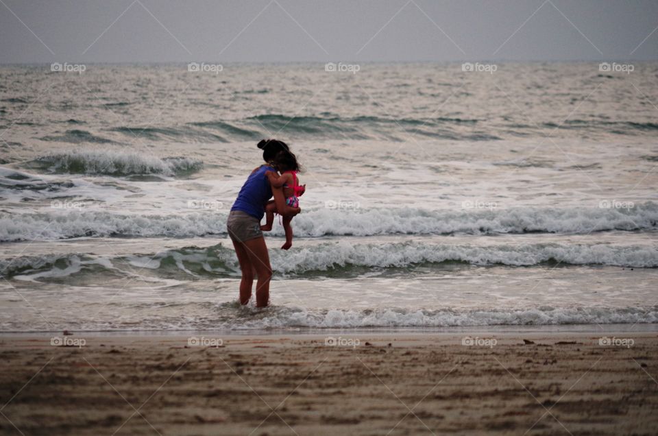 Mother carrying her kid on the beach.  Love concept.