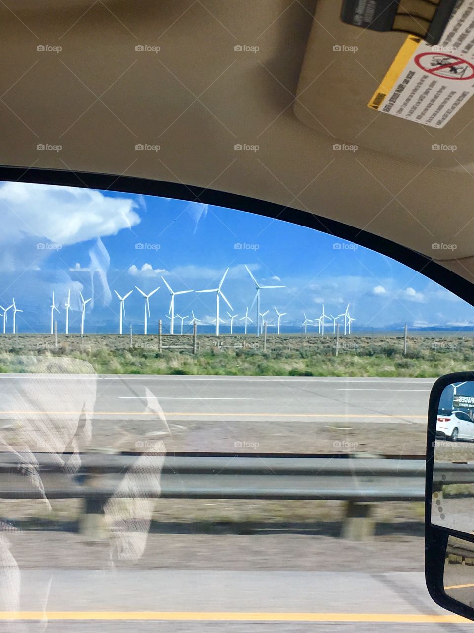 Energy efficiency huge windmills. Wyoming road trip. Windows view. Blue sky drive. Large white wind mills. Mountain of Wyoming.