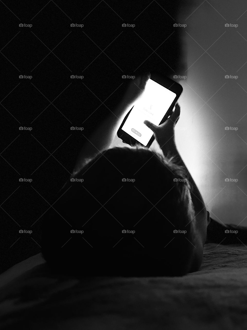 Close up shot of a boy playing with the phone in the dark