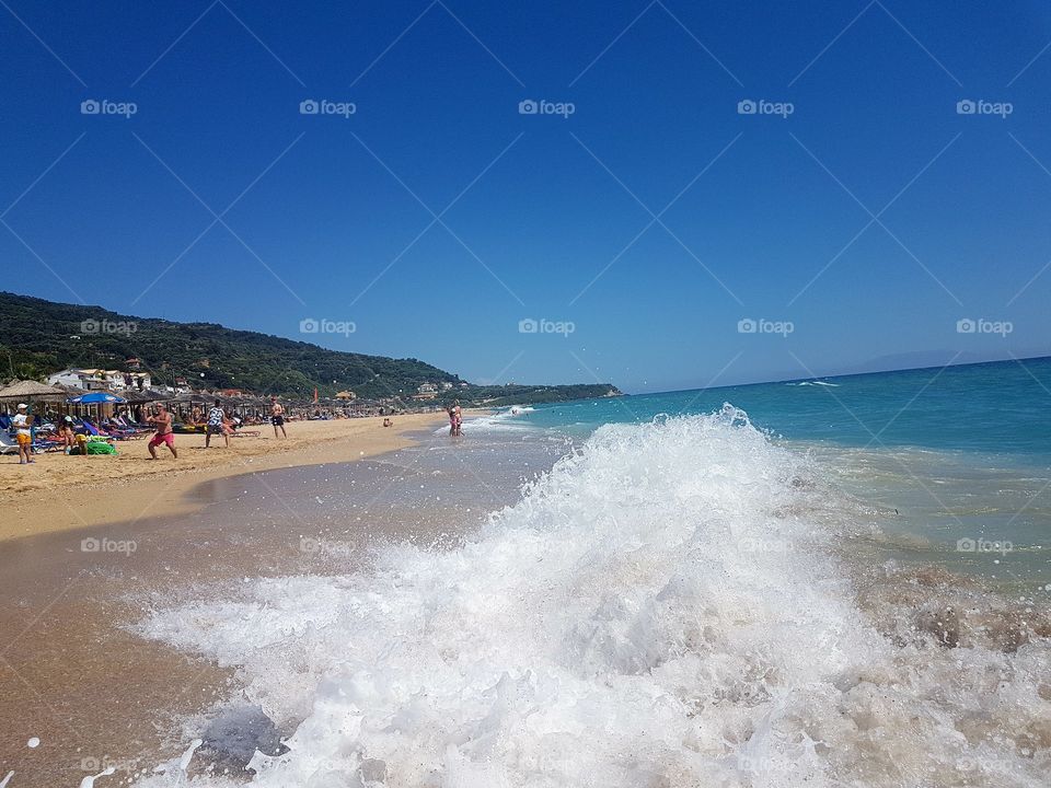 Beach waves on Vrachos beach Greece. Ionian sea. Crystal clear water. 3.5km long sandy beach