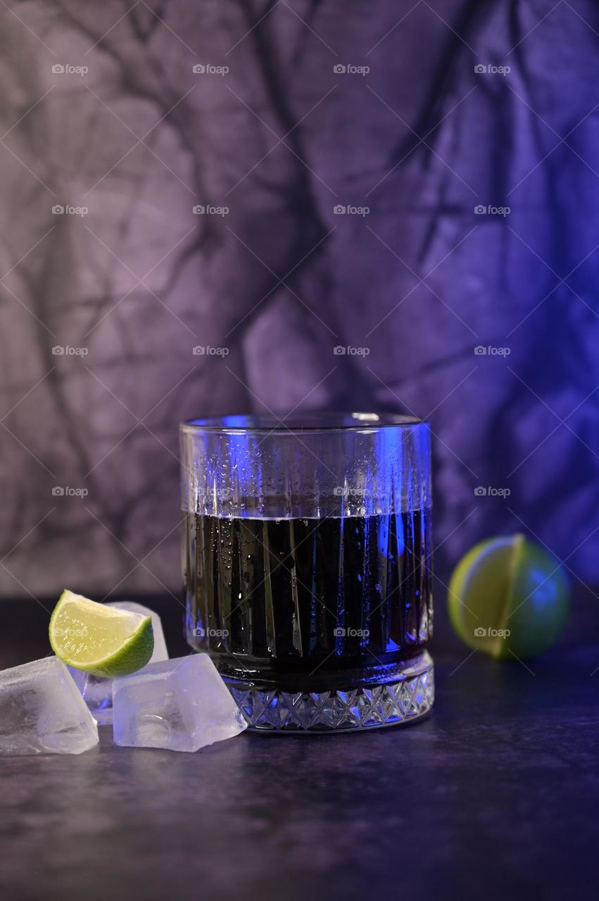 A Glass of Cold Sparkling Soda Water on Dark Background, Ice Cube and Lime Near a Glass