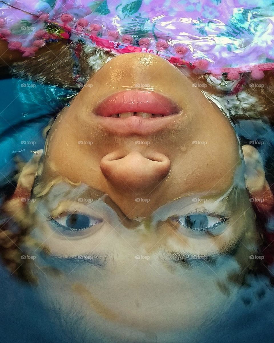 Menina com metade do rosto dentro da água 
