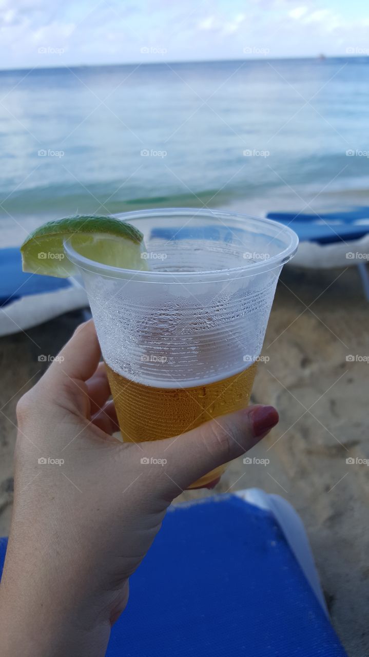 woman hand holding beer on the beach