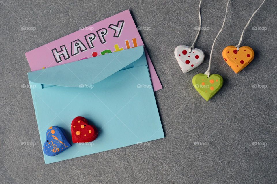 Multicolored wooden hearts near a greeting card