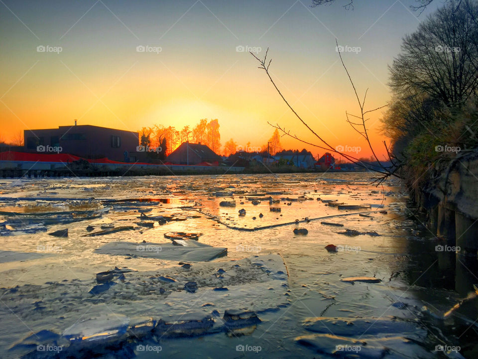 Ice floating on a frozen river under a colorful sunset in the winter