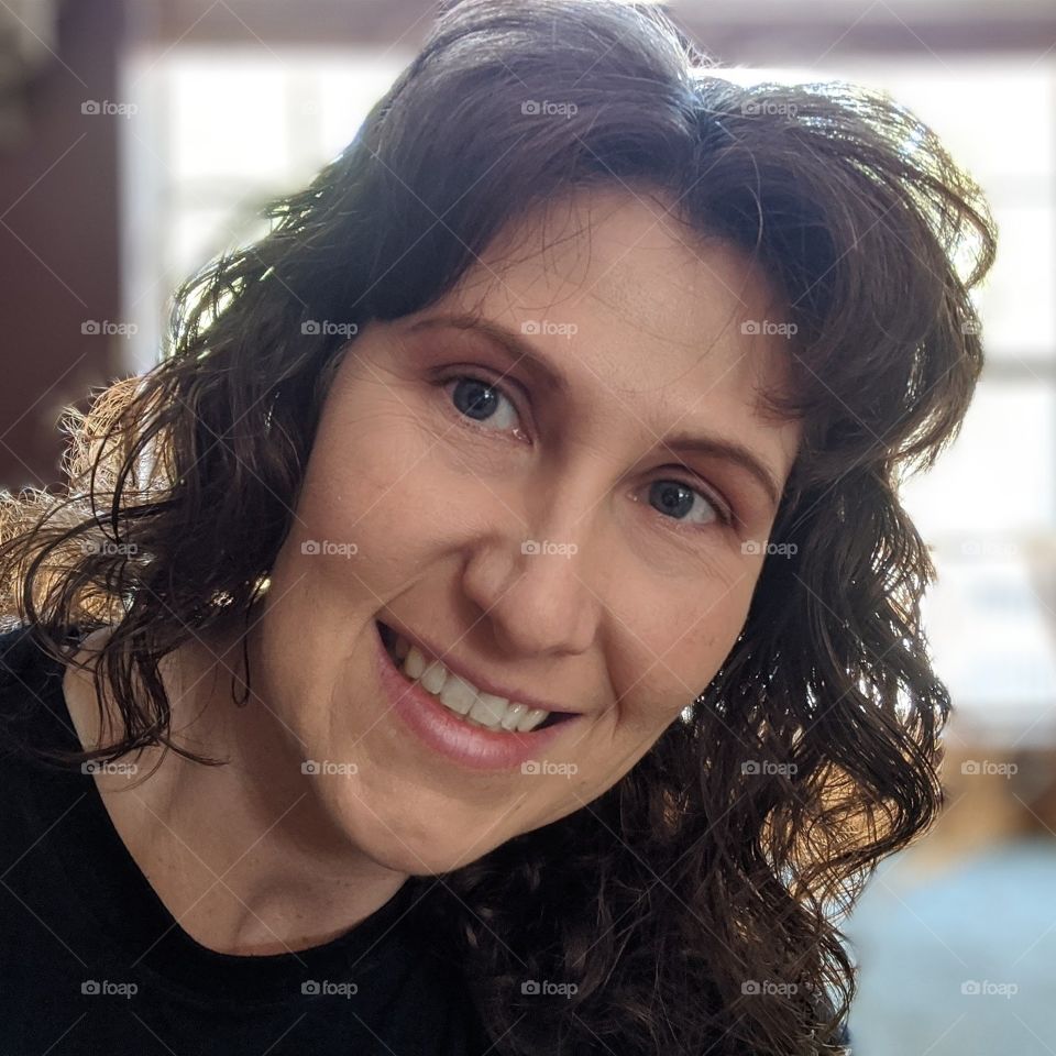 woman smiling and peaking around a corner