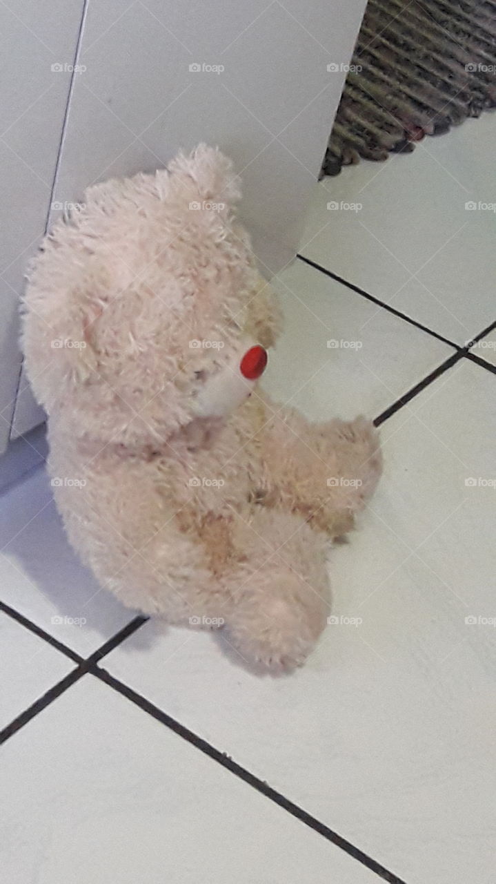 Urso de pelúcia sentado no chão.