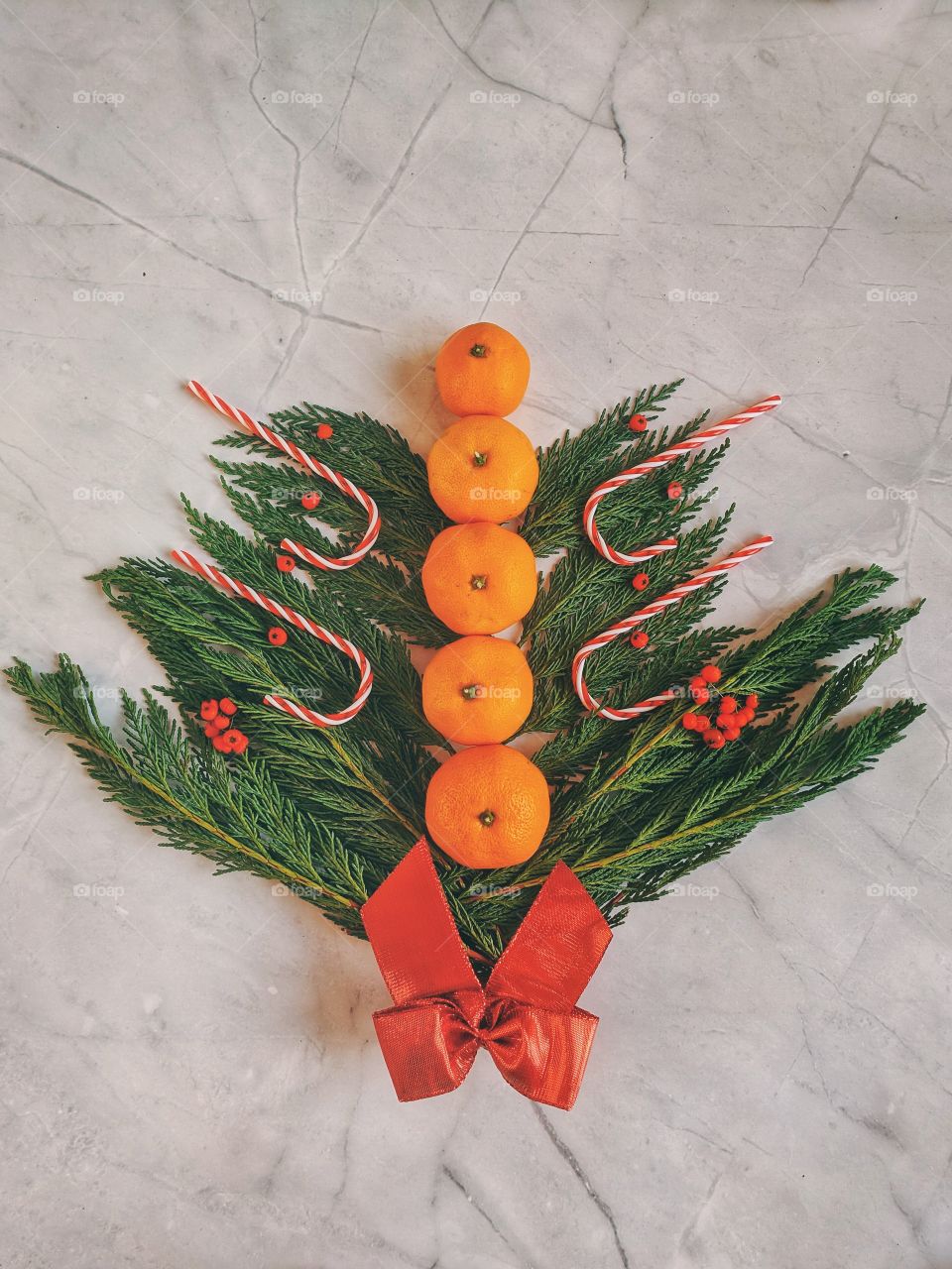 Christmas and New Year background with spruce branch, candies, decorations and tangerines Flat lay. Top view.