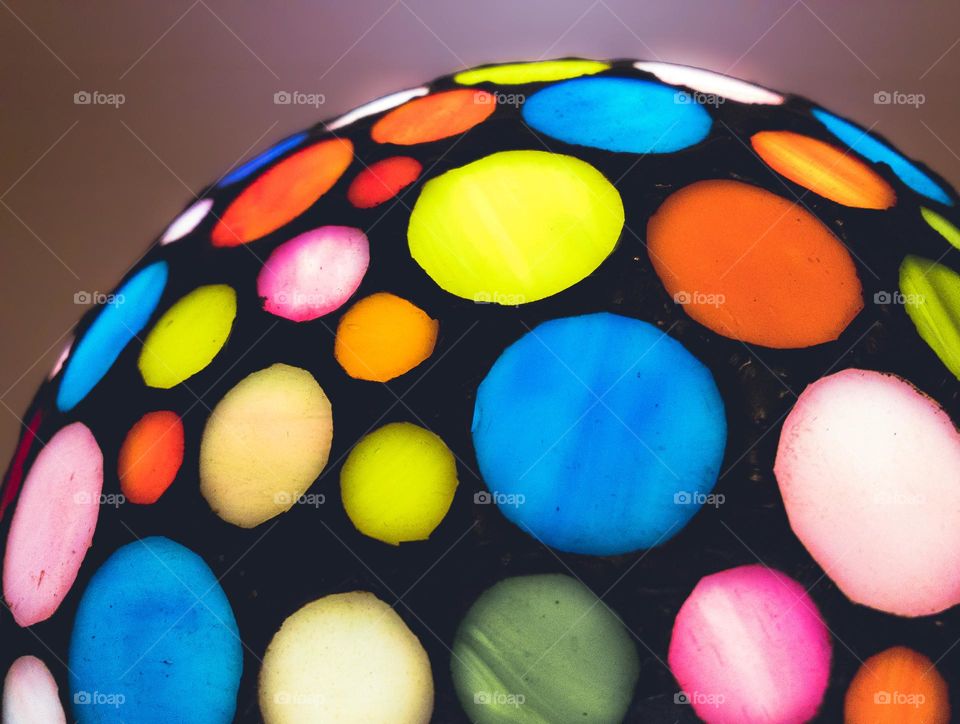 Part of a modern Tiffany style lamp, covered in coloured circles of stained glass