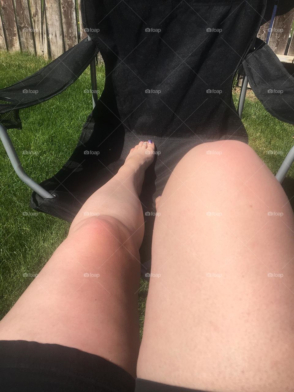 Middle aged lady’s bare extended and bent legs so to suntan