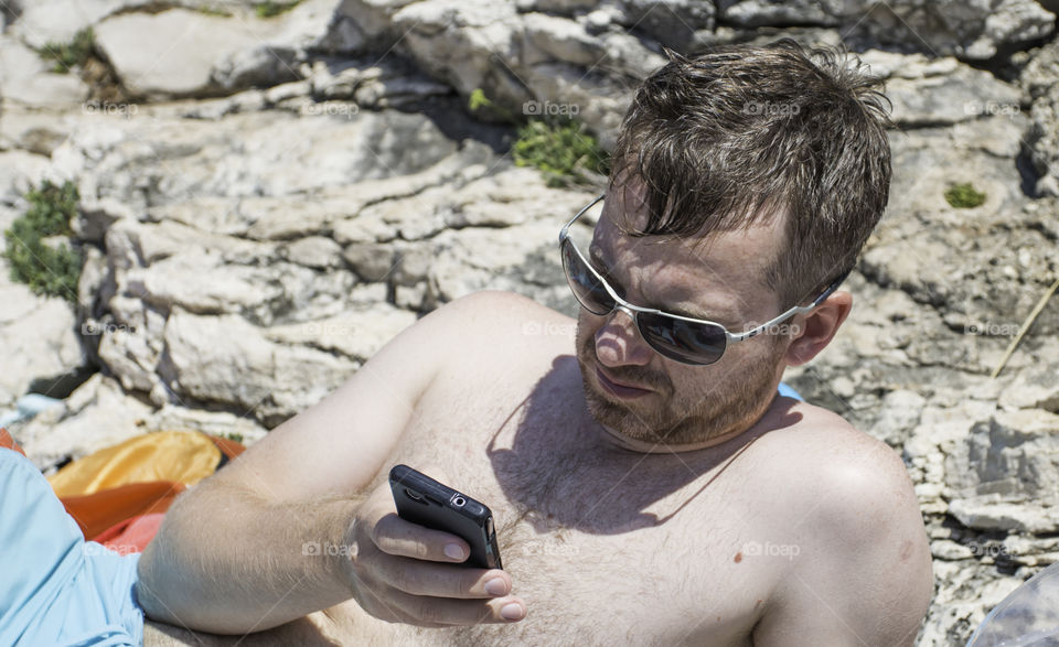 man and smartphone on the beach