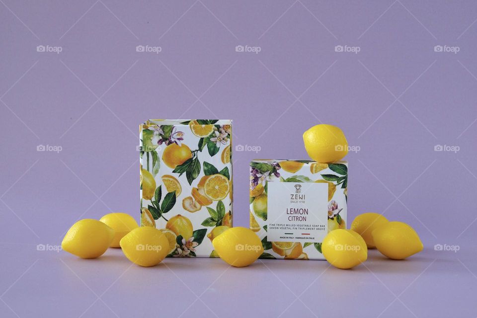 Close-up of soap box and lemon shaped soaps isolated on lavender background.