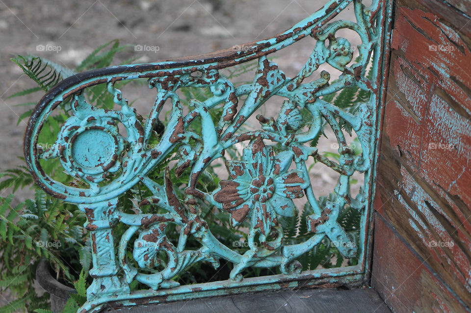Texture & pattern: The patterned metal arm of a wooden bench has either been deliberately distressed or age has naturally created a beautiful rust & turquoise patina. In addition the distressed wood of the bench gives it a very vintage appearance.