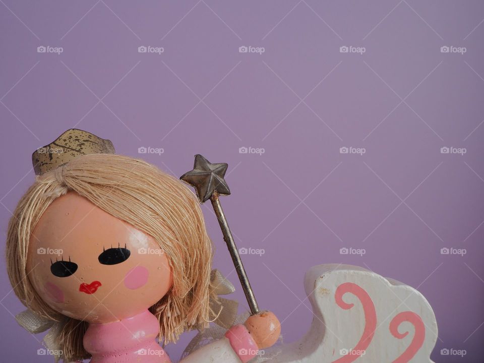 Antique, wooden, fantasy princess with magic wand on purple background 