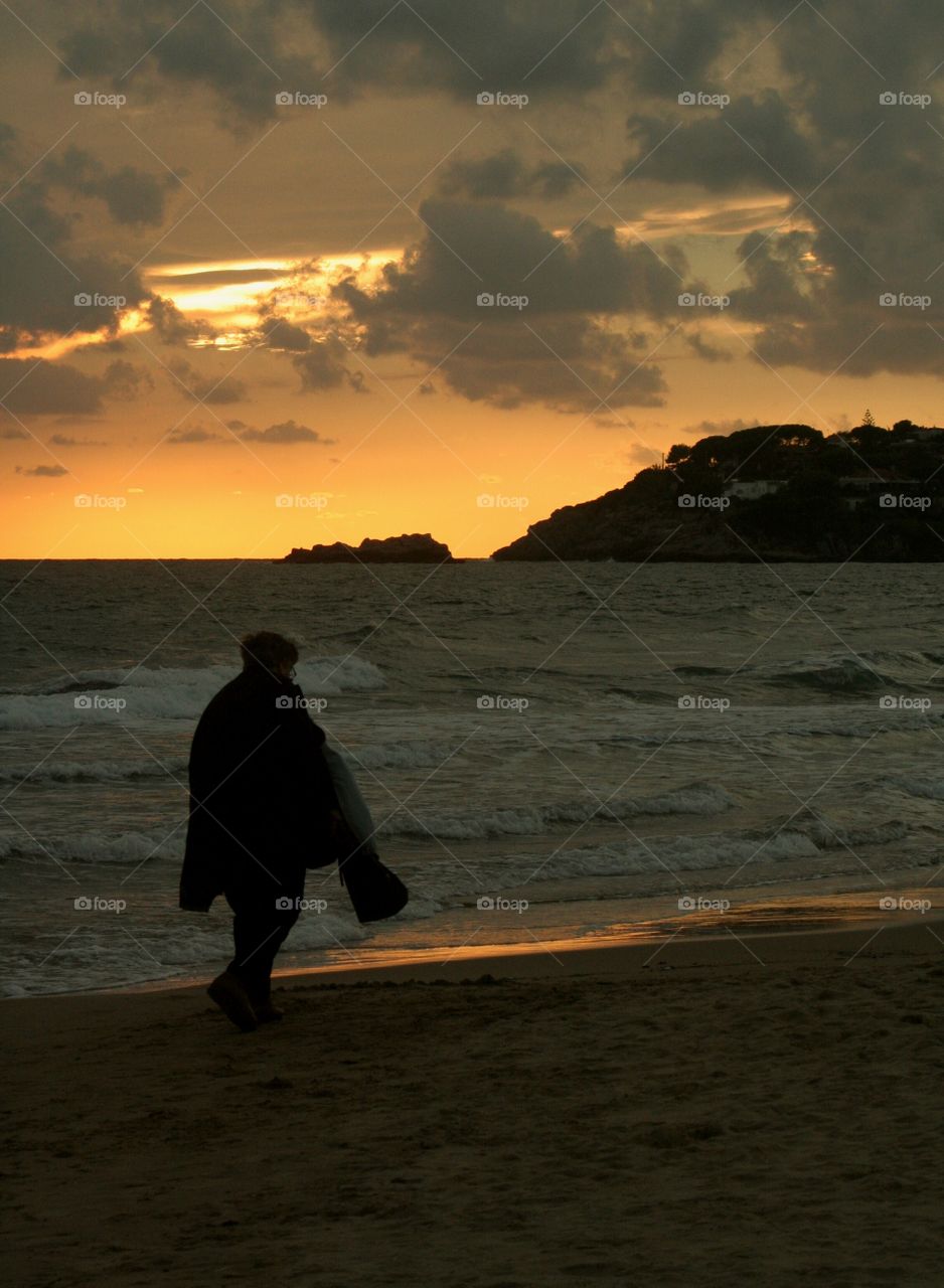 Woman taking a walk on beach at sunset