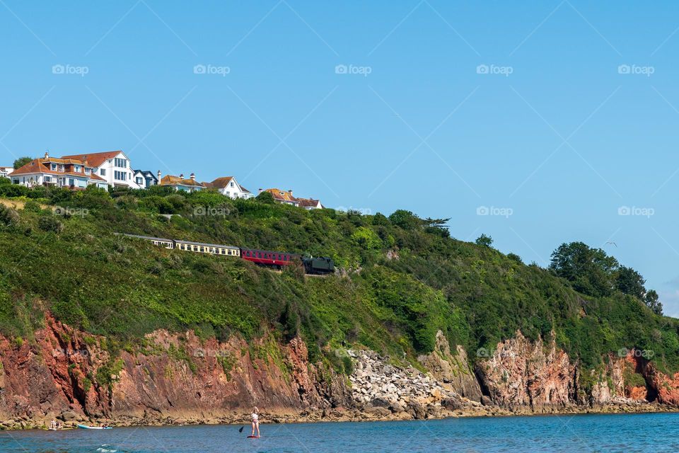 Summer paddle boarding underneath cliff rocks with retro train.