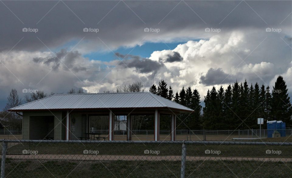 park with pavillion building, large white clouds and offset dark clouds