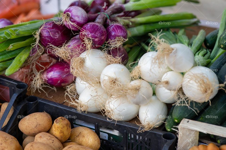 red onions and spring onions on a market stall