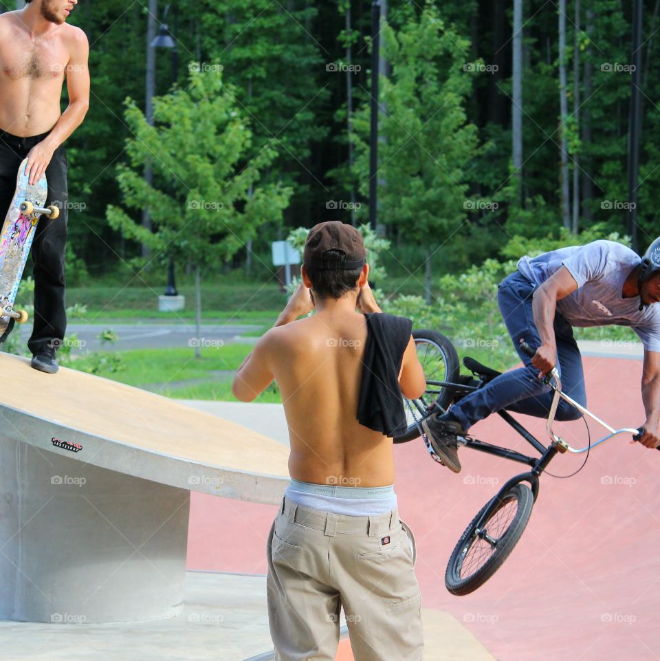 Center of the Action - man taking pictures of skater and biker doing tricks at skate park