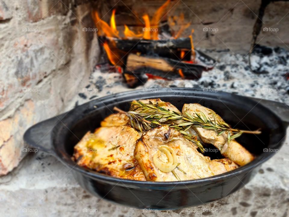 food cooked outdoors in a black cast iron dish with open fire in the background
