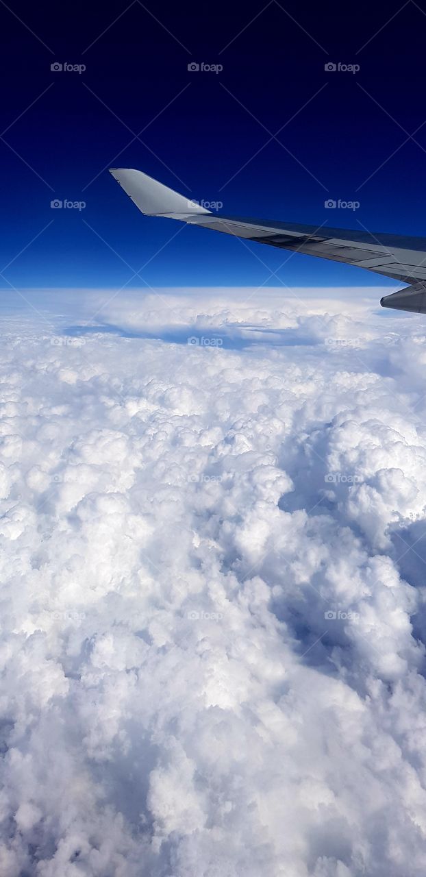 Fluffy white clouds below, blue sky above - view from an aeroplane window