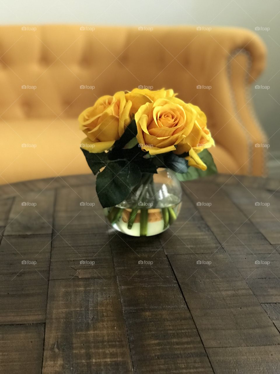 Yellow roses vase on wooden table on the background a yellow couch