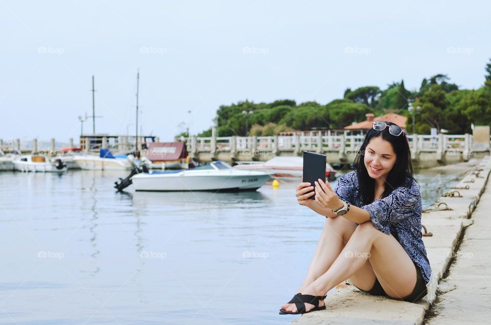 Portrait of young happy business woman relaxing,  working in city, beach at Adriatic sea. Laptop. Technology.  Selfie.  Social media.  Video call.