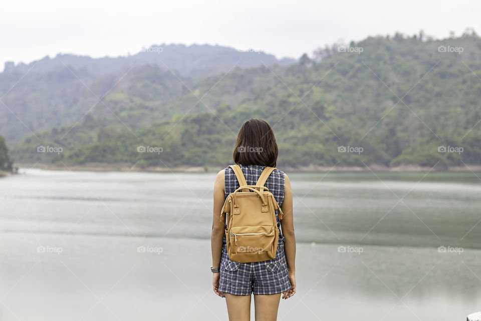 Women shoulder backpack Background mountains and water at Wang Bon dam ,Nakhon nayok in Thailand.