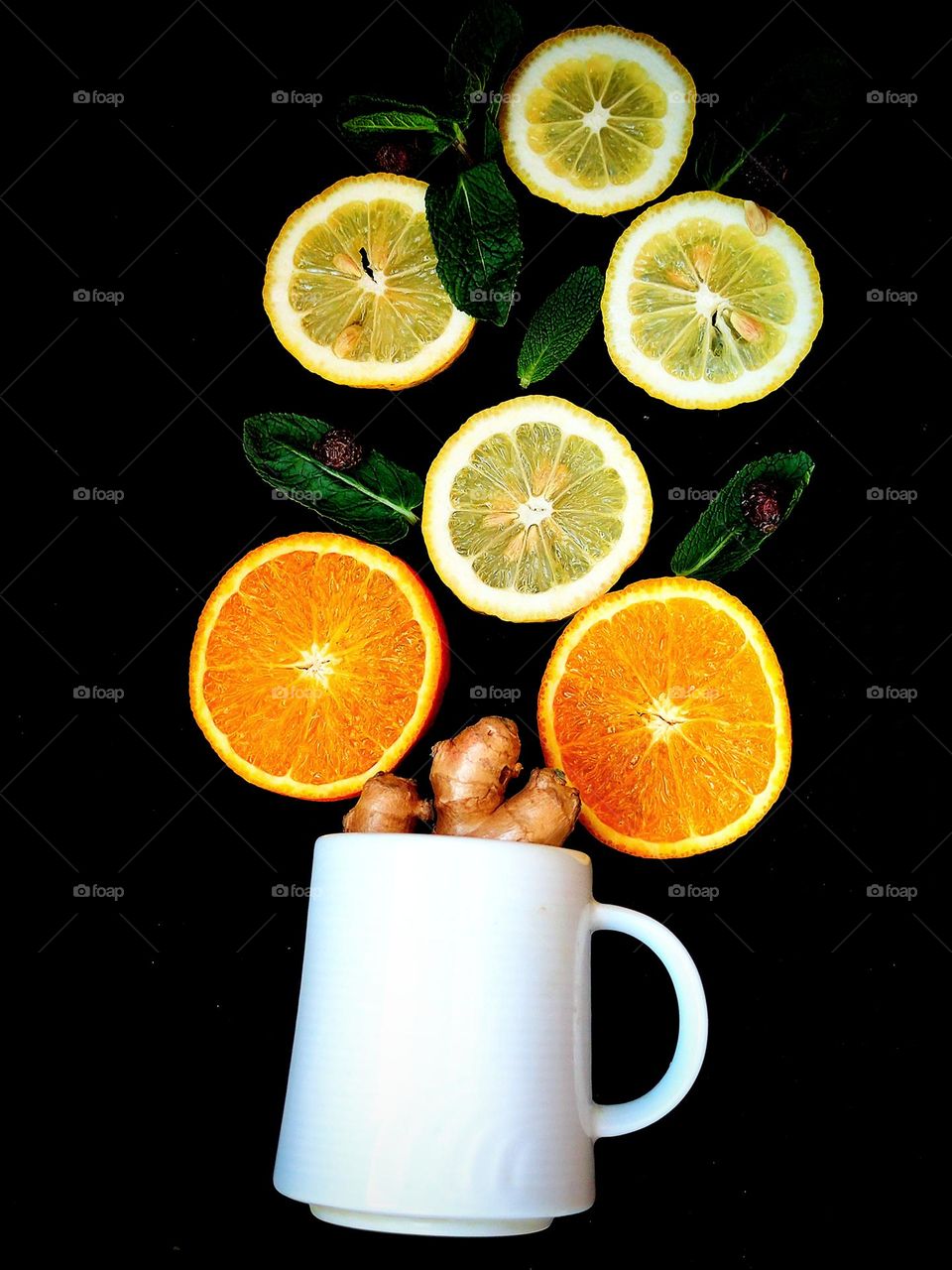 Fruit. A white mug from which a tree grows: trunk - ginger root, flowers: mugs of orange orange and mugs of yellow lemon, leaves - green mint leaves. Black background. Fruit tree