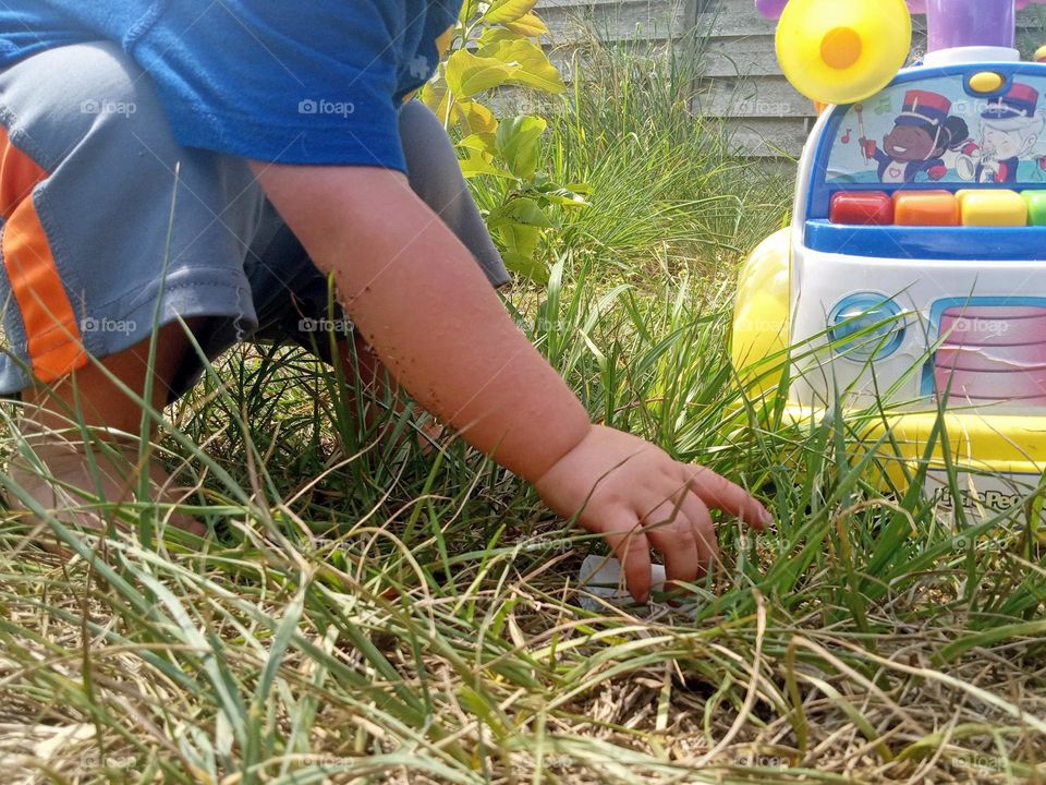 A toddler at play outside in the grass